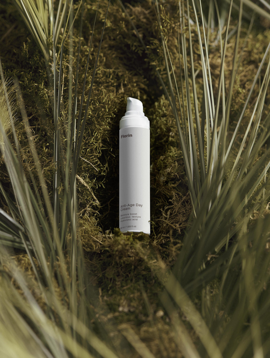 White spray bottle on a bed of green moss and grass